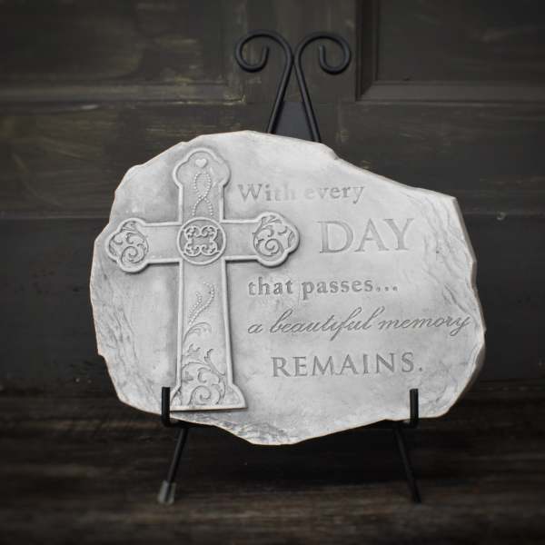 Decorative memorial plaque with a cross and engraved quote on a stand