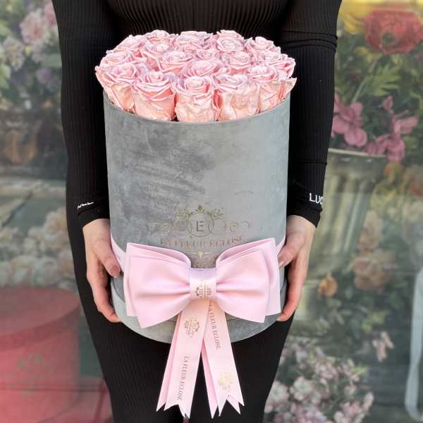 Pink roses arranged in a gray hat box with a large pink bow