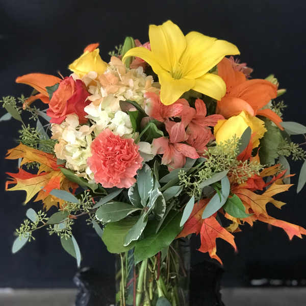 Bouquet of lilies, roses, hydrangea, and carnations in a glass vase