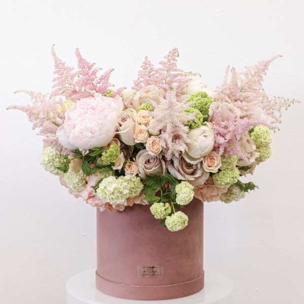 Pink and cream floral arrangement in a velvet hat box