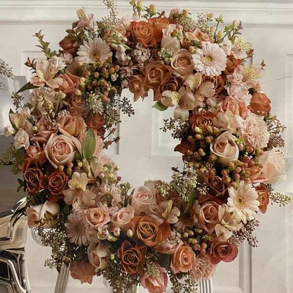 Large floral wreath of peach and blush roses with daisy-like blooms