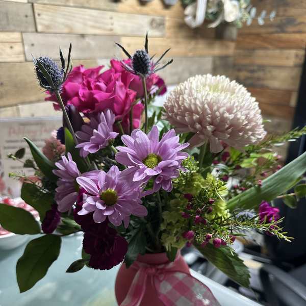 Pink and lavender mixed bouquet in a pink vase with ribbon