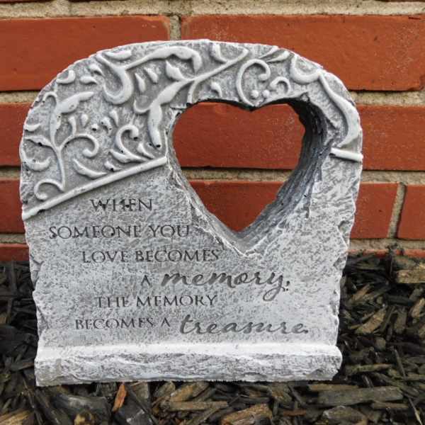 Heart-shaped memorial stone with an engraved quote against a brick wall