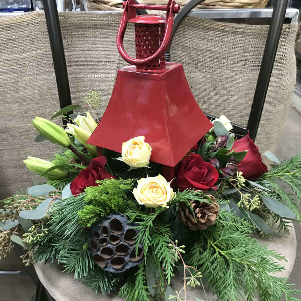 Red lantern centerpiece with roses and lilies on evergreen foliage