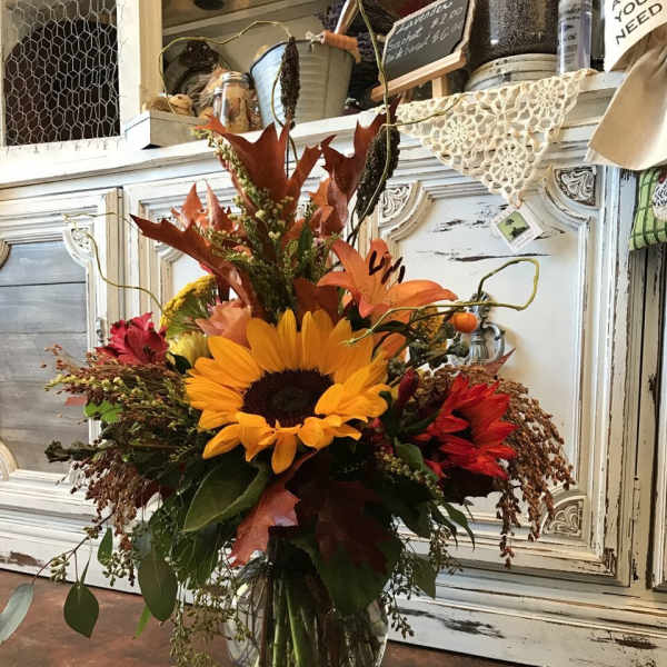 Autumn bouquet with a sunflower and orange lilies in a glass vase