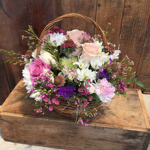 Basket arrangement of pink and white flowers with a wicker handle