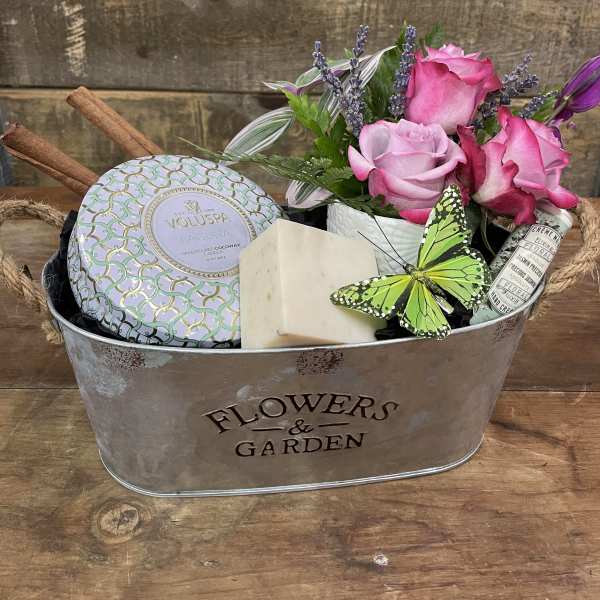 Pink roses in a metal gift basket with candles and soap