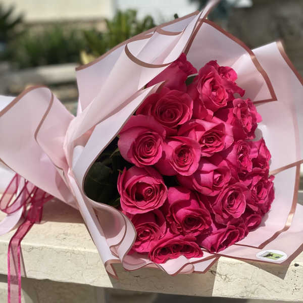 Bouquet of bright pink roses wrapped in pale pink paper