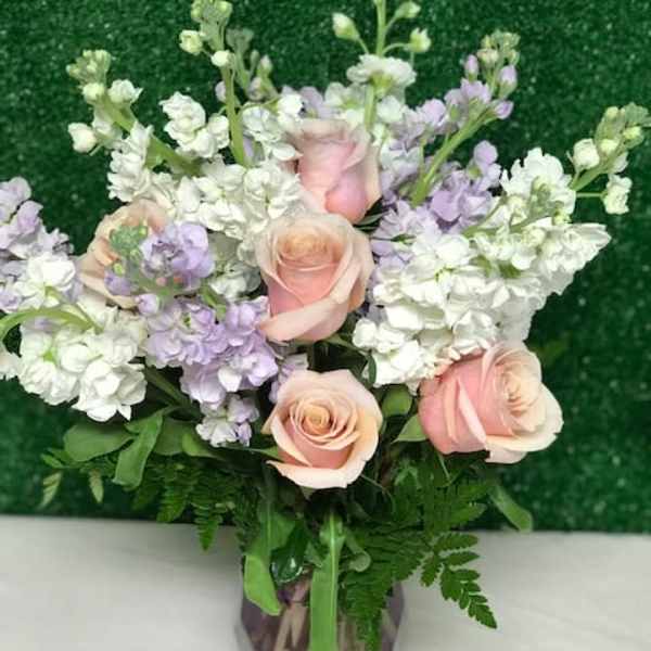 Pink roses and white-lavender flowers in a glass vase