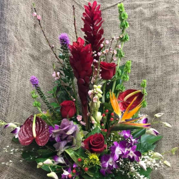 Mixed tropical bouquet with red roses and purple orchids in a dark vase