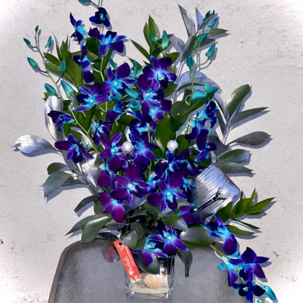 Purple and blue orchid arrangement in a clear glass vase