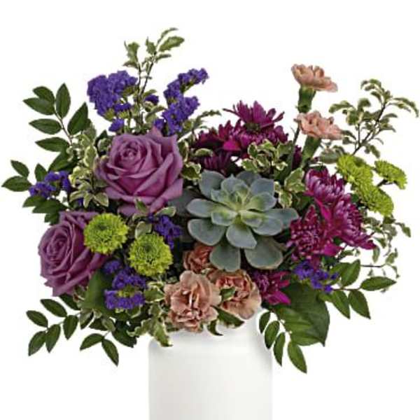 Purple and magenta floral arrangement in a white vase with a succulent centerpiece