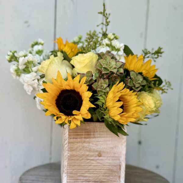 Sunflowers and pale yellow roses in a wooden box arrangement