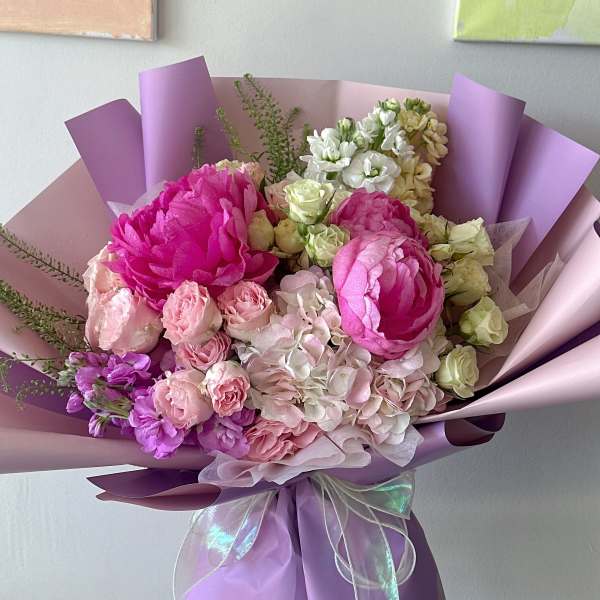 Bouquet of pink and white flowers wrapped in lavender paper