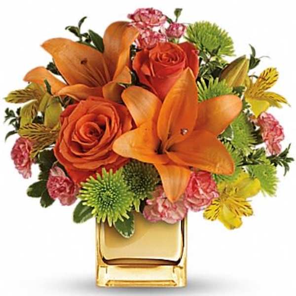 Orange lilies and roses in a square glass vase