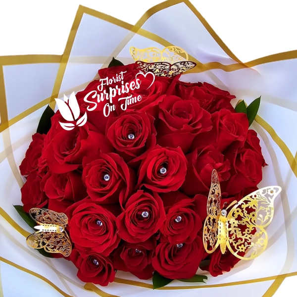 Bouquet of red roses wrapped in white and gold paper with butterfly decorations