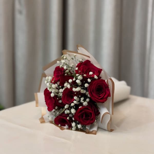 Bouquet of red roses with white baby's breath in paper wrap