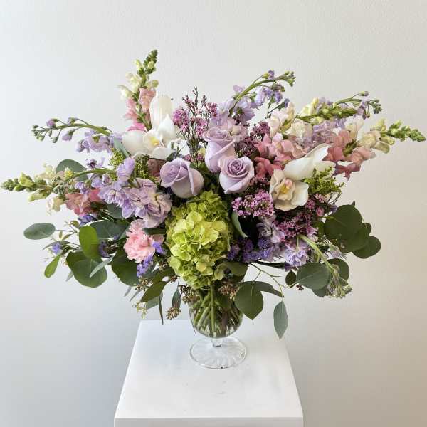Pastel bouquet of roses, hydrangea, and orchids in a glass vase