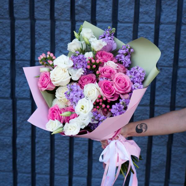 Bouquet of pink, white, and purple roses wrapped in pastel paper