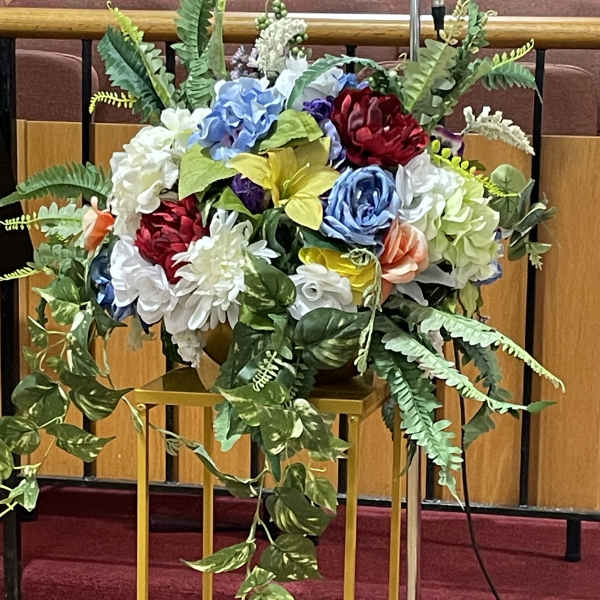 Large floral arrangement with multicolored blooms and trailing greenery on a stand