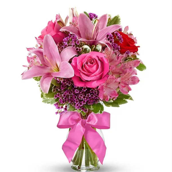 Pink roses and lilies in a glass vase with a pink ribbon