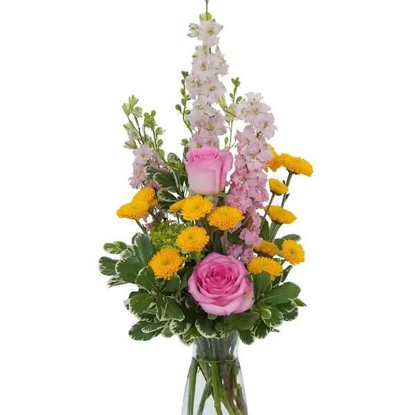 Pink roses and yellow pompon flowers in a clear glass vase