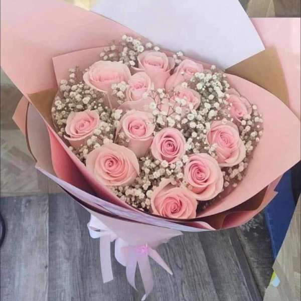Bouquet of pale pink roses with baby's breath in pastel wrapping