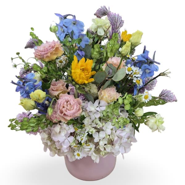 Mixed bouquet in a pink vase with blue, yellow, and pastel flowers