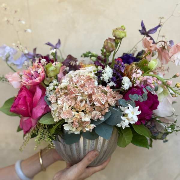 Mixed bouquet in a ribbed vase with pink, white, and purple blooms