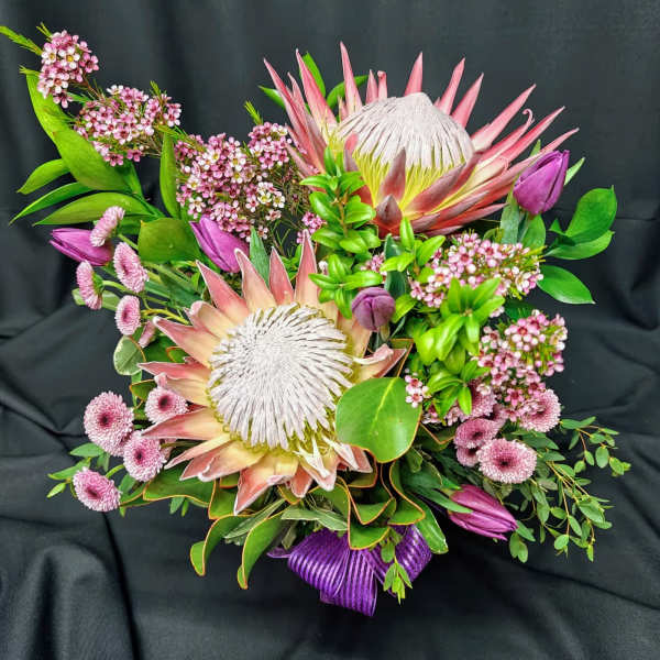 Pink and white protea bouquet with purple buds and green foliage