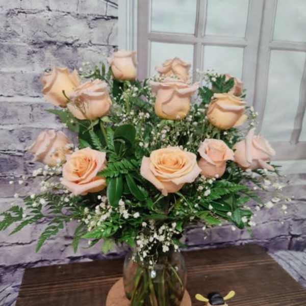Peach roses arranged in a glass vase with baby's breath
