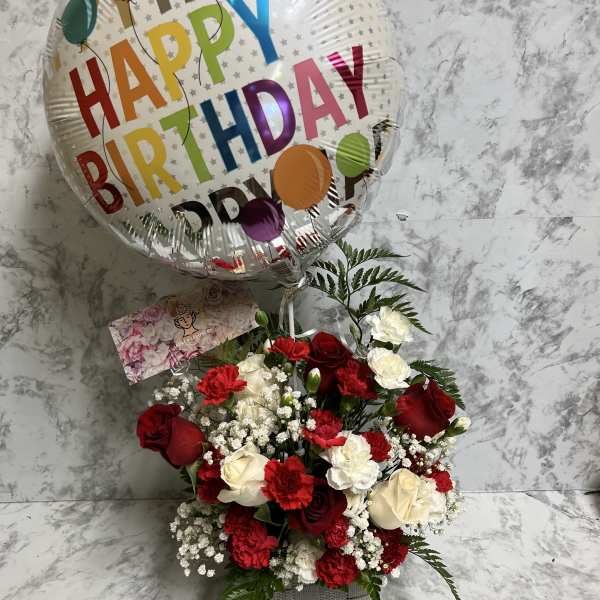 Red and white flower arrangement with a Happy Birthday balloon in a gray container