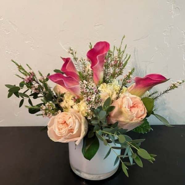 Pink calla lilies and blush roses in a white vase