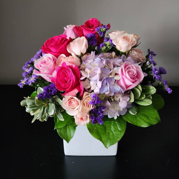 Pink and lavender rose bouquet in a white square vase