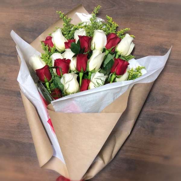 Hand-tied bouquet of red and white roses wrapped in kraft paper with a red ribbon