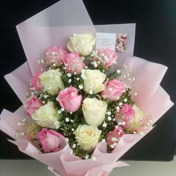 Bouquet of pink and white roses wrapped in pale pink paper
