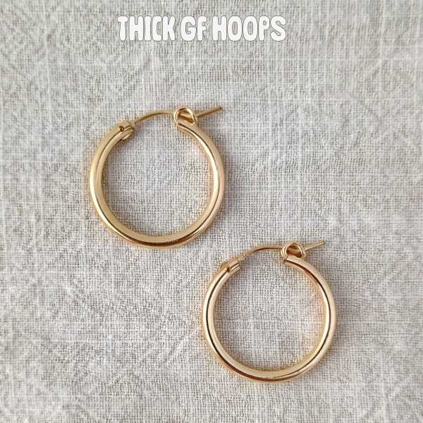 Pair of gold hoop earrings on a textured fabric background