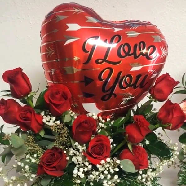 Red roses arranged around a heart balloon that says I Love You.