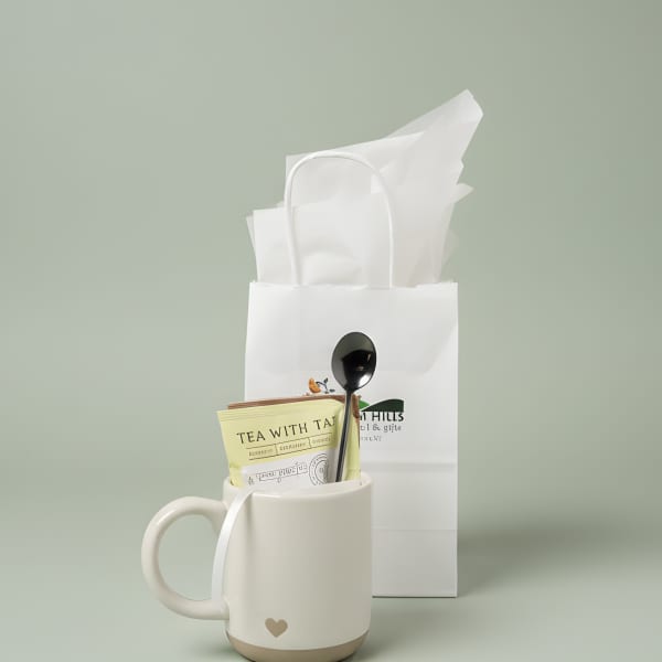 White mug gift set with tea packet and spoon in a paper bag