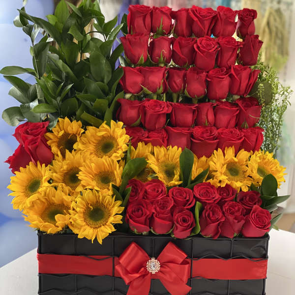 Red roses and yellow sunflowers arranged in a black box with a red ribbon
