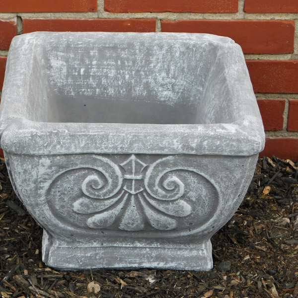 Empty gray stone planter with decorative scrollwork