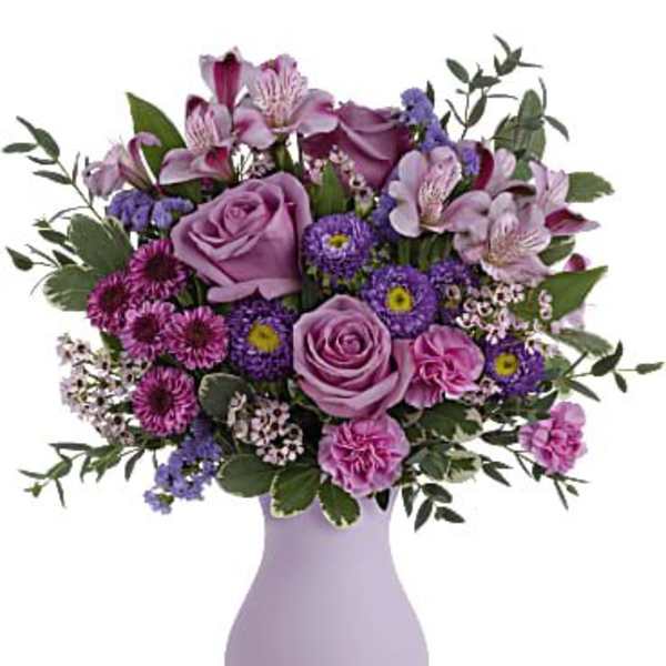 Lavender vase holding pink and purple mixed flowers