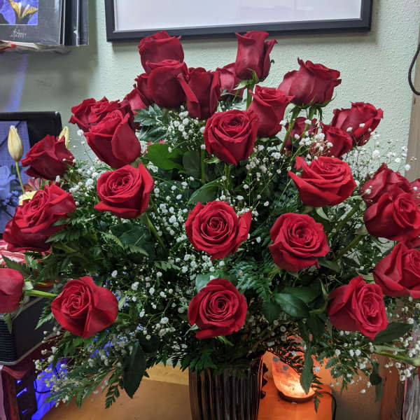 Tall vase arrangement of red roses with baby's breath