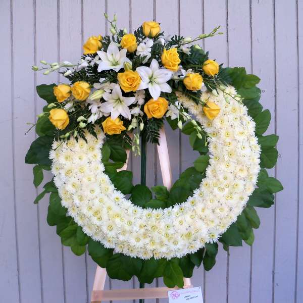 Yellow roses and white lilies arranged in a large floral wreath