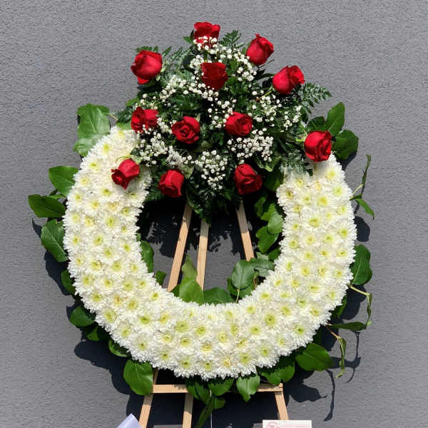 White chrysanthemum wreath with red roses on a standing easel