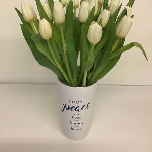 White tulips in a white vase with a peace message