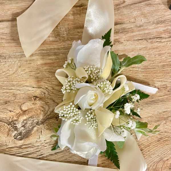 White rose corsage with cream ribbon and small white filler flowers