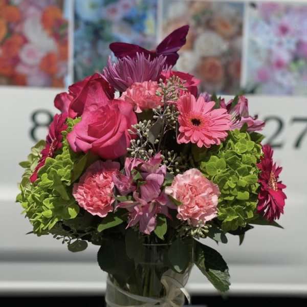 Pink and magenta bouquet in a glass vase with a ribbon