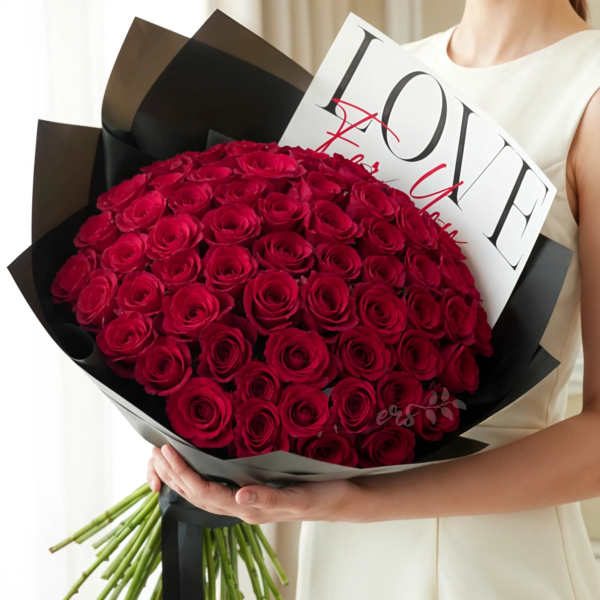 Large bouquet of red roses wrapped in black paper with a love card