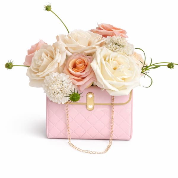 Pink handbag with cream and peach roses arranged on top